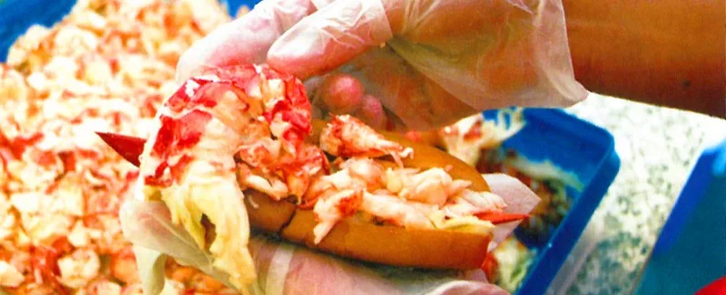 Close-up of a hand holding a fresh Red's Eats lobster roll